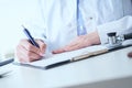 Female medicine doctor hand holding silver pen writing something on clipboard closeup. Royalty Free Stock Photo