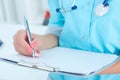 Female medicine doctor hand holding silver pen writing something on clipboard closeup. Royalty Free Stock Photo