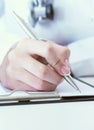 Female medicine doctor hand holding silver pen writing something on clipboard closeup. Royalty Free Stock Photo