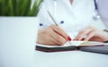 Female medicine doctor hand holding silver pen writing something on clipboard and working laptop closeup. Physician Royalty Free Stock Photo