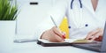 Female medicine doctor hand holding silver pen writing something on clipboard and working laptop closeup. Physician Royalty Free Stock Photo