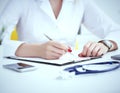 Female medicine doctor hand holding silver pen writing something on clipboard and working laptop closeup. Physician Royalty Free Stock Photo