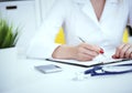 Female medicine doctor hand holding silver pen writing something on clipboard and working laptop closeup. Physician Royalty Free Stock Photo