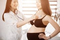 Female medicine doctor holding stethoscope to pregnant woman standing for encouragement, empathy, cheering, support