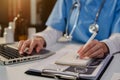 Doctor, physician or practitioner in lab room writing on blank notebook and work on laptop computer.