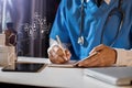 Doctor, physician or practitioner in lab room writing on blank notebook and work on laptop computer. Royalty Free Stock Photo