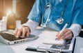 Female medicine doctor, physician or practitioner in lab room writing on blank notebook and work on laptop computer. Royalty Free Stock Photo