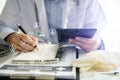 Female medicine doctor, physician or practitioner in lab room writing on blank notebook and work on laptop computer. Royalty Free Stock Photo