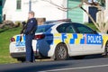 A female member of the New Zealand police and a police car