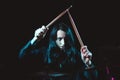 A female metal drummer with long hair holding up drumsticks behind the drumkit against a dark background Royalty Free Stock Photo