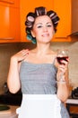 Female middle-aged housewife in the kitchen with glass of wine