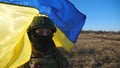 Female military medic of ukrainian army looks into camera against waving blue-yellow banner. Portrait of girl in Royalty Free Stock Photo