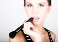 Female model applying makeup on her face. Beautiful young woman applying foundation on her face with a make up brush. Royalty Free Stock Photo