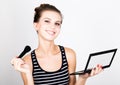 Female model applying makeup on her face. Beautiful young woman applying foundation on her face with a make up brush. Royalty Free Stock Photo