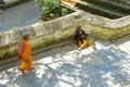 Female monk walks towards a beggar sitting by stairs inside Pashupatinath Temple