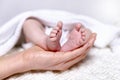 Female mother hands holding tiny feet of a newborn baby Royalty Free Stock Photo