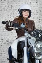 Female motorcyclist in open helmet holds steering wheel while sitting on the motorbike