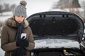 Female Motorist Broken Down In Snow Calling For Roadside Assistance On Mobile Phone