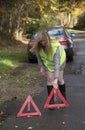 Female motorist placing red warning triangles in the road, Royalty Free Stock Photo