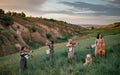 Female musical quartet with violins and cello plays on flowering meadow next to sitting dog. Royalty Free Stock Photo