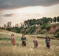 Female musical quartet with violins and cello stands on flowering meadow. Royalty Free Stock Photo