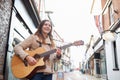 Female Musician Busking Playing Acoustic Guitar Outdoors In Street