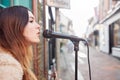 Female Musician Busking Playing Acoustic Guitar And Singing Outdoors In Street