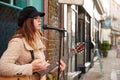 Female Musician Busking Playing Acoustic Guitar And Singing Outdoors In Street