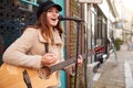 Female Musician Busking Playing Acoustic Guitar And Singing Outdoors In Street Royalty Free Stock Photo