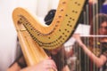 Female musician harpist playing harp during symphonic concert, with other musicians in the background, close up hands of the woman Royalty Free Stock Photo