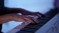 female musician is playing electric piano at home at darkness, closeup of hands over keys Royalty Free Stock Photo