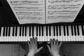 Female musician seated at a grand piano playing a melodic tune, with sheet music in view behind her