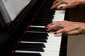 Female musician seated at a grand piano playing a melodic tune, with sheet music in view behind her