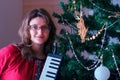 A female musician stands near a Christmas tree Royalty Free Stock Photo