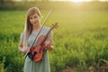 Female musician violinist holding a violin in her hands in sunset light