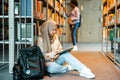 Female muslim student sitting on floor in library and reading book Royalty Free Stock Photo