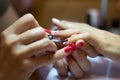 Female nail painting. Manicurist applying transparent varnish on little finger nail during final step of her work. Royalty Free Stock Photo