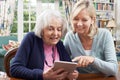 Female Neighbor Showing Senior Woman How To Use Digital Tablet