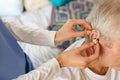 Female nurse applying hearing aid to senior male patient ear Royalty Free Stock Photo