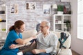 Female nurse attaching digital device on old mans arm