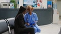 Female nurse consulting young woman in hospital waiting area