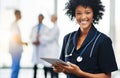 Female nurse or doctor holding a tablet with colleagues standing in the background. Confident, smiling healthcare Royalty Free Stock Photo