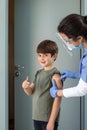 Female Nurse with gloves puts a band aid on a boy& x27;s arm after vaccination. Royalty Free Stock Photo