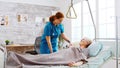 Female nurse helping an old disabled and retired woman to go to bed Royalty Free Stock Photo