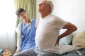 Female nurse helping senior male patient with back pain