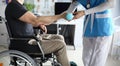 Female nurse helps lift dumbbell to disabled patient rehabilitation therapy