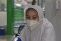 a female nurse in indonesia in an outpatient room wears a mask and is on duty in the morning