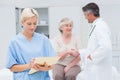 Female nurse making reports while doctor and patient shaking hands Royalty Free Stock Photo