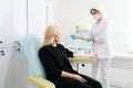 Female nurse in mask and gloves preparing test collection for lady patient. Woman waiting medical examination in clinic Royalty Free Stock Photo