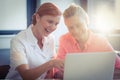 Female nurse and senior woman smiling while using laptop Royalty Free Stock Photo